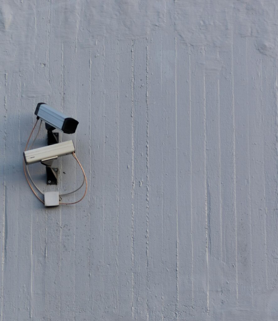 Two surveillance cameras mounted on a wall for security and safety monitoring.