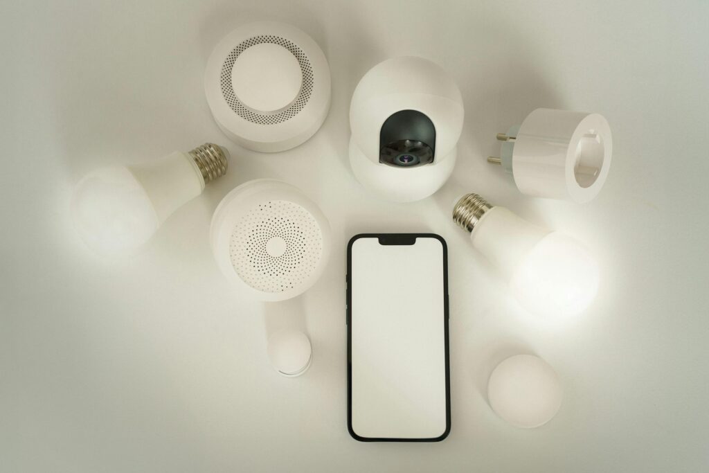 Flat lay of smart home devices with a smartphone controller on a white background.